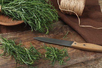 Photo of Fresh whole and cut tarragon sprigs on wooden table