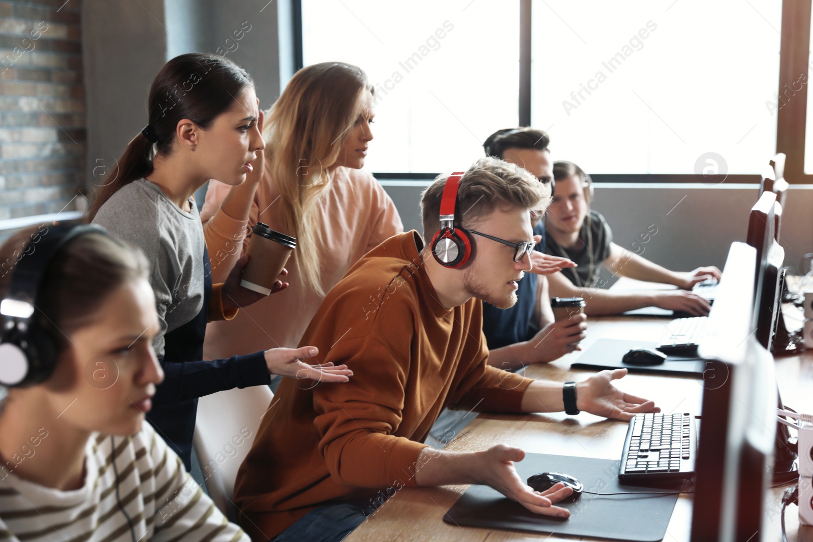 Photo of Group of people playing video games in internet cafe