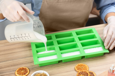 Photo of Woman making natural handmade soap at wooden table, closeup