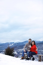 Couple sitting on bench in mountains. Winter vacation