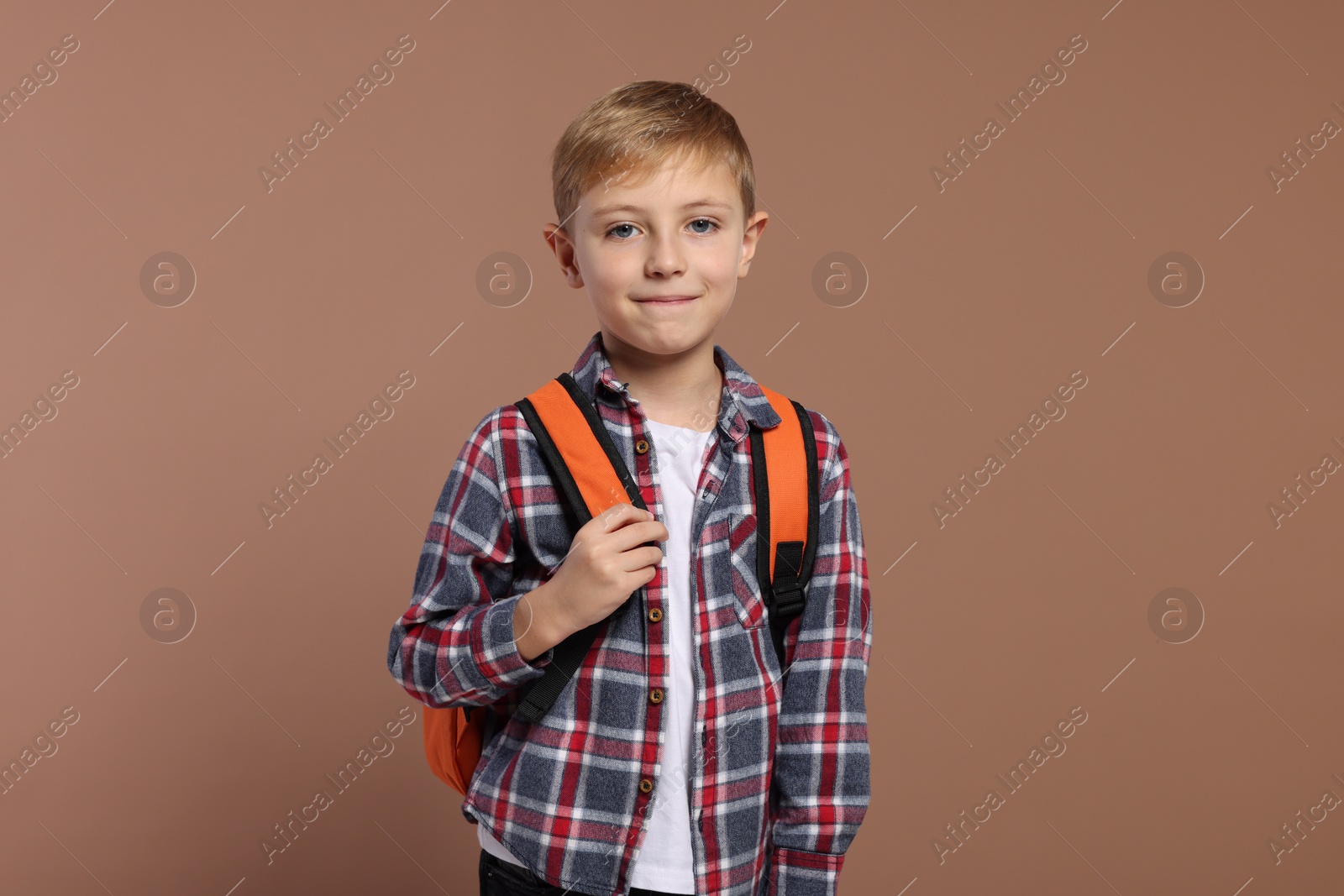 Photo of Happy schoolboy with backpack on brown background