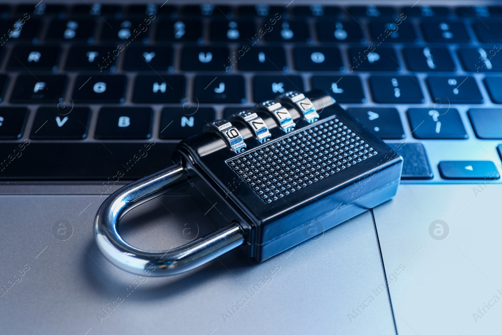 Photo of Cyber security. Metal combination padlock on laptop, closeup