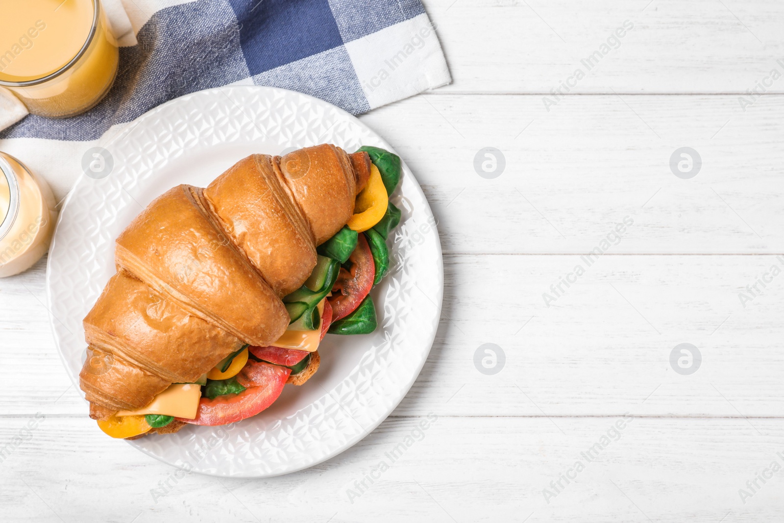 Photo of Tasty vegetarian croissant sandwich on white wooden table, flat lay. Space for text