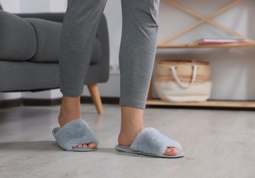 Photo of Woman wearing light blue soft slippers at home, closeup