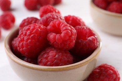 Tasty ripe raspberries in bowl on white table, closeup