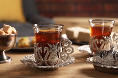 Glasses of traditional Turkish tea in vintage holders on wooden table