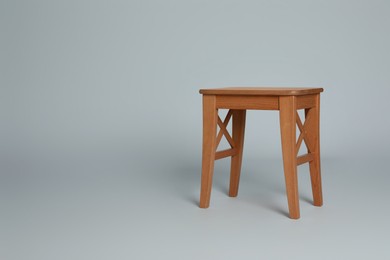 Photo of Stylish wooden stool on light grey background. Space for text