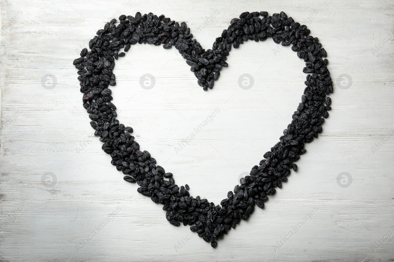 Photo of Frame made of raisins on wooden background, top view with space for text. Dried fruit as healthy snack