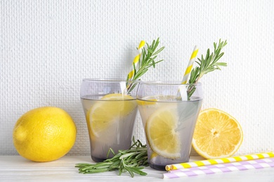 Photo of Tasty refreshing lemon cocktail with rosemary on table