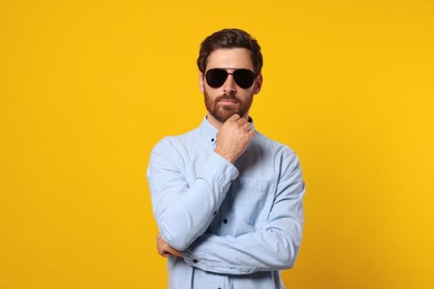 Photo of Portrait of bearded man with stylish sunglasses on orange background