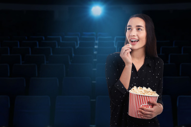 Woman with popcorn in cinema, space for text
