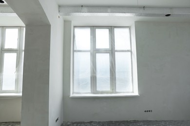 Windows covered with plastic film in spacious room