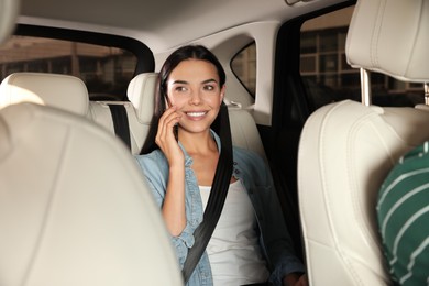 Photo of Young woman talking on phone in modern taxi