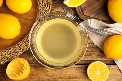 Photo of Freshly squeezed lemon juice on wooden table, flat lay