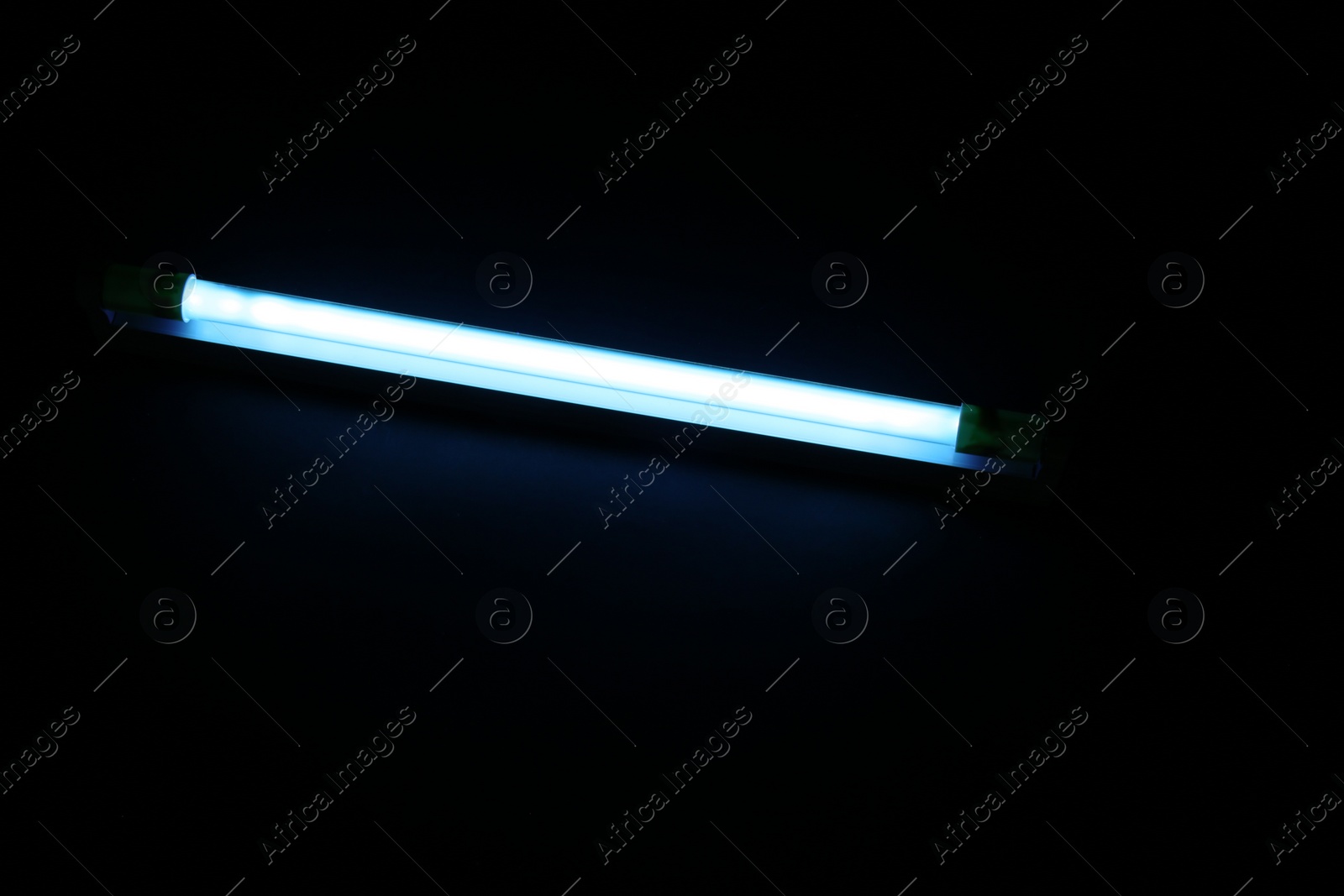 Photo of Modern ultraviolet lamp glowing on black background