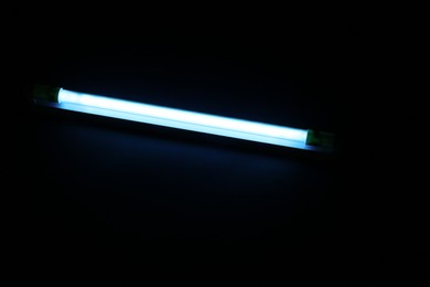 Modern ultraviolet lamp glowing on black background