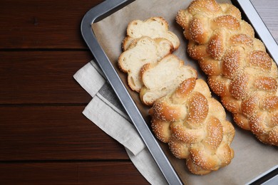 Photo of Baking tray with homemade braided bread on wooden table, top view and space for text. Traditional Shabbat challah