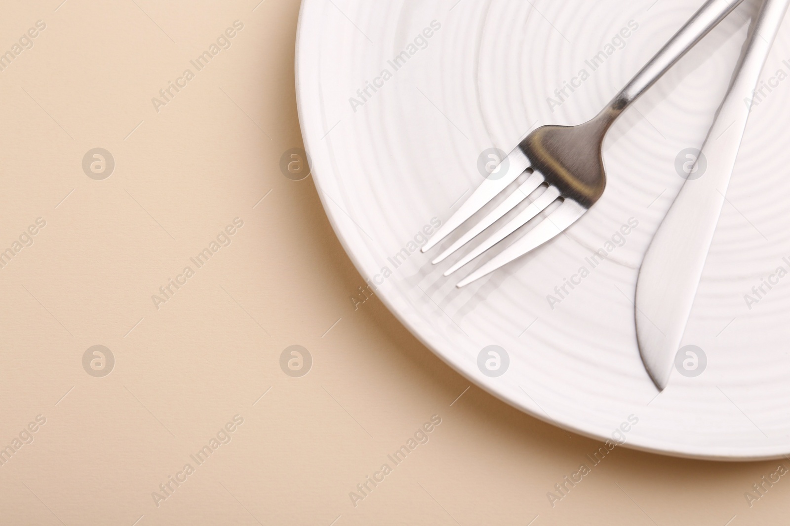 Photo of Setting with stylish cutlery on beige table, top view. Space for text