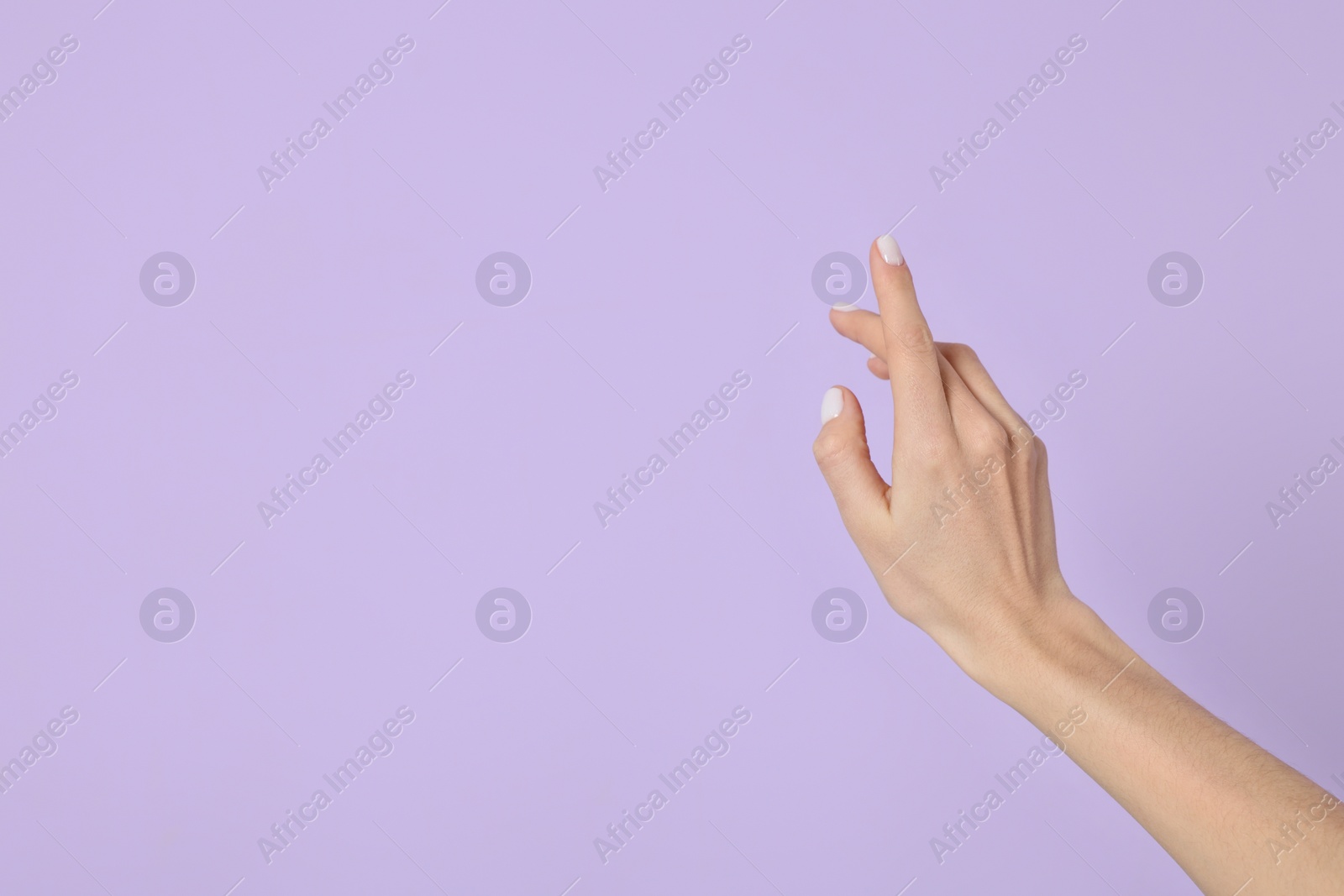 Photo of Woman holding something against violet background, closeup on hand. Space for text