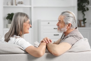 Photo of Affectionate senior couple relaxing on sofa at home