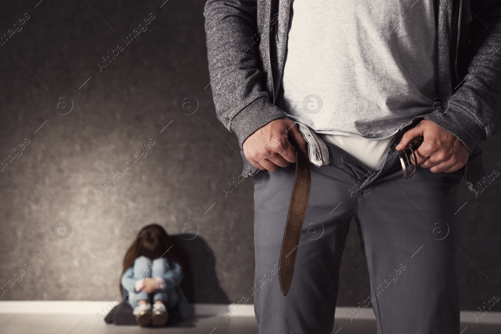 Photo of Man with unzipped pants and scared little girl indoors, space for text. Child in danger