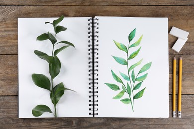 Painting of green twig in sketchbook and art supplies on wooden table, flat lay