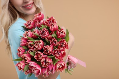 Photo of Happy woman holding beautiful bouquet on beige background, closeup. Space for text