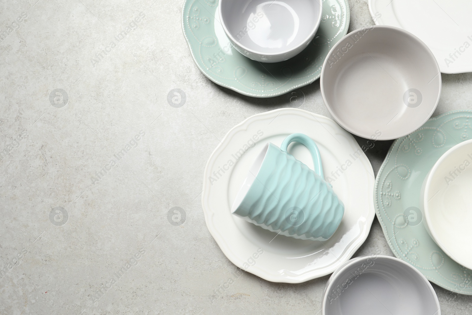 Photo of Beautiful ceramic dishware and cup on light grey table, flat lay. Space for text