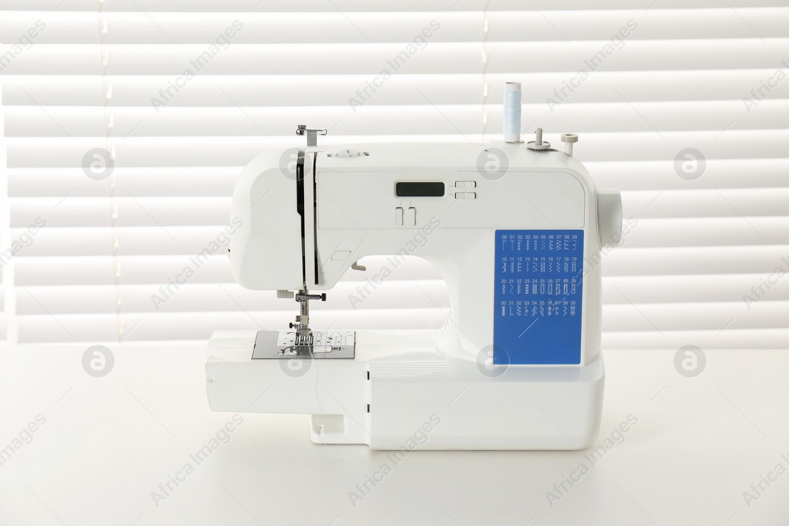 Photo of Sewing machine on white desk in workshop