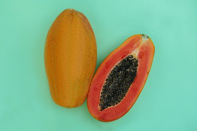 Photo of Fresh ripe papaya fruits on light turquoise background, flat lay