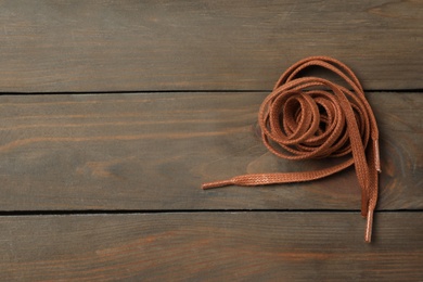 Photo of Brown shoelaces on wooden background, top view. Space for text