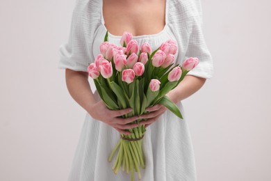 Photo of Woman with bouquet of beautiful fresh tulips on light grey background, closeup