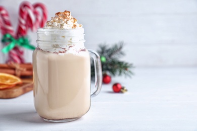 Photo of Delicious Christmas liqueur with whipped cream on white table, closeup. Space for text