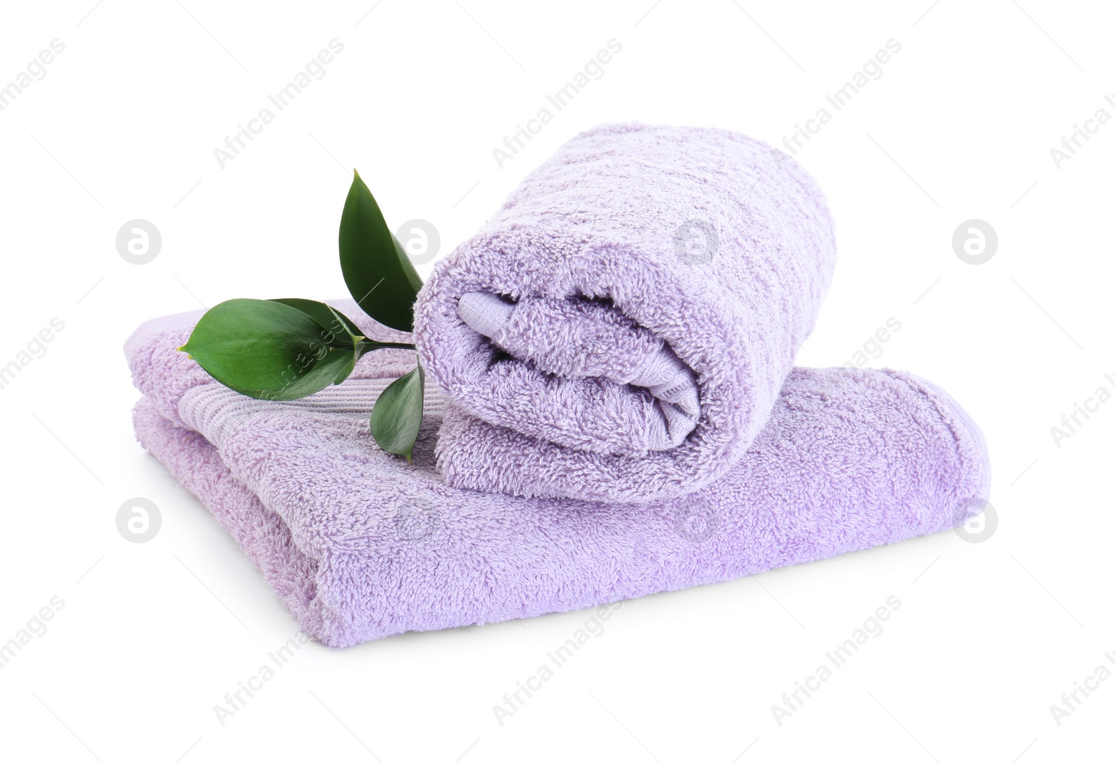 Photo of Violet terry towels and green leaves isolated on white