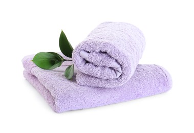Violet terry towels and green leaves isolated on white
