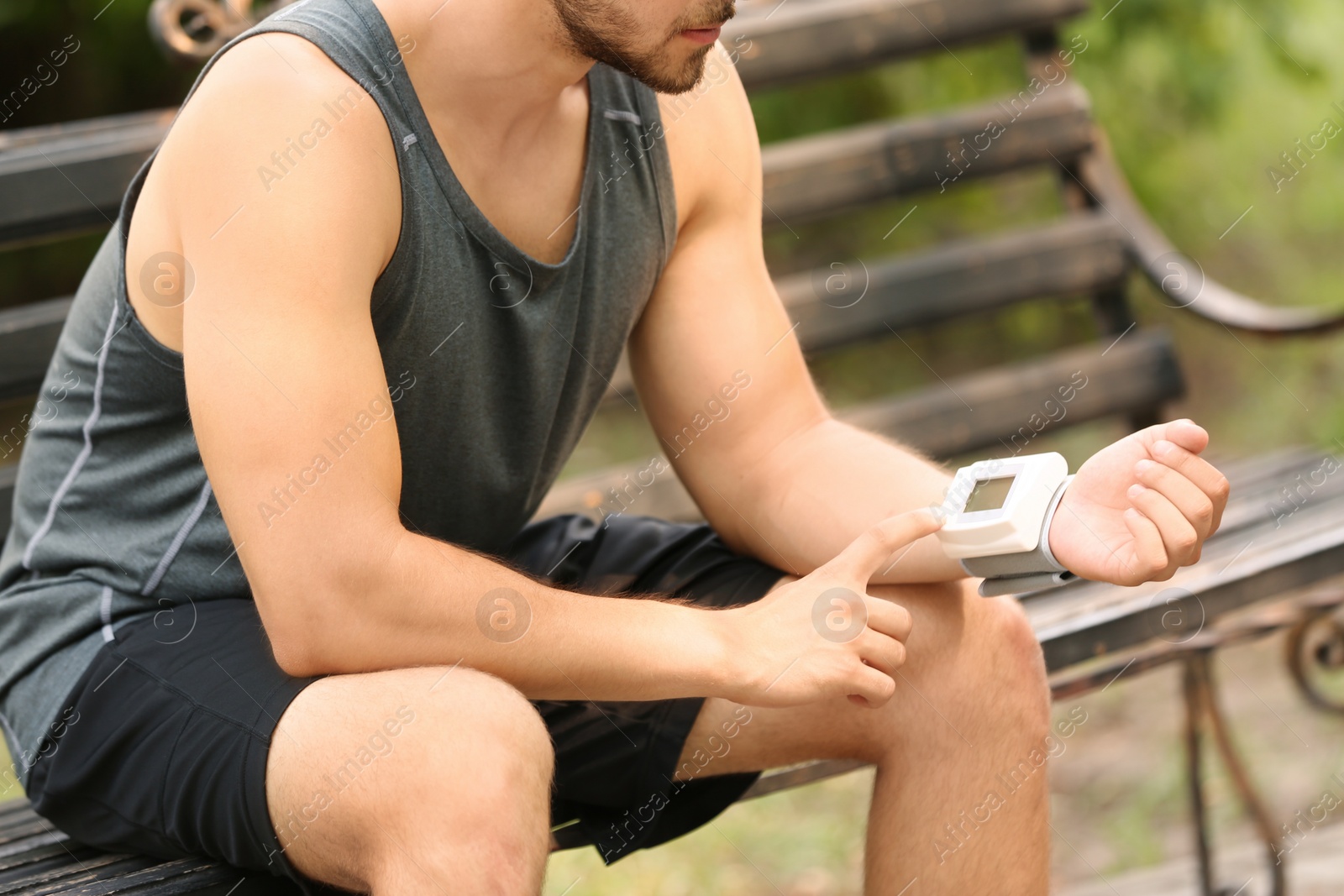 Photo of Young man checking pulse outdoors on sunny day