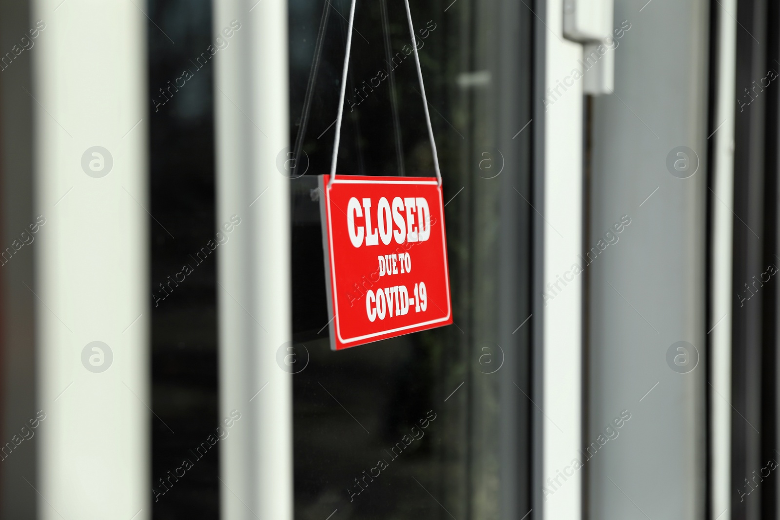 Photo of Red sign with text Closed Due To Covid-19 hanging on glass door. Coronavirus quarantine