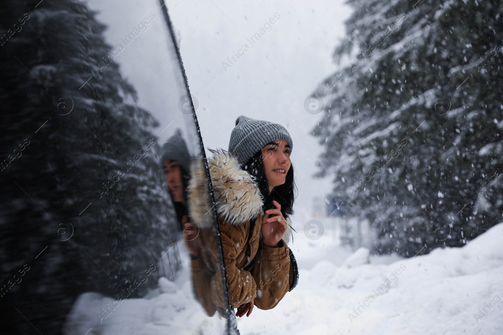 Photo of Young woman looking out of car window on snowy day