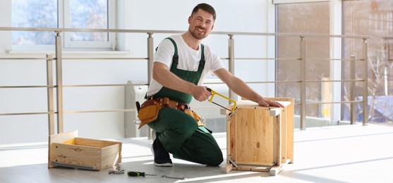 Image of Carpenter in uniform making furniture indoors. Banner design