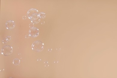 Many beautiful soap bubbles on light brown background. Space for text