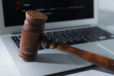 Photo of Laptop and wooden gavel on light table. Cyber crime