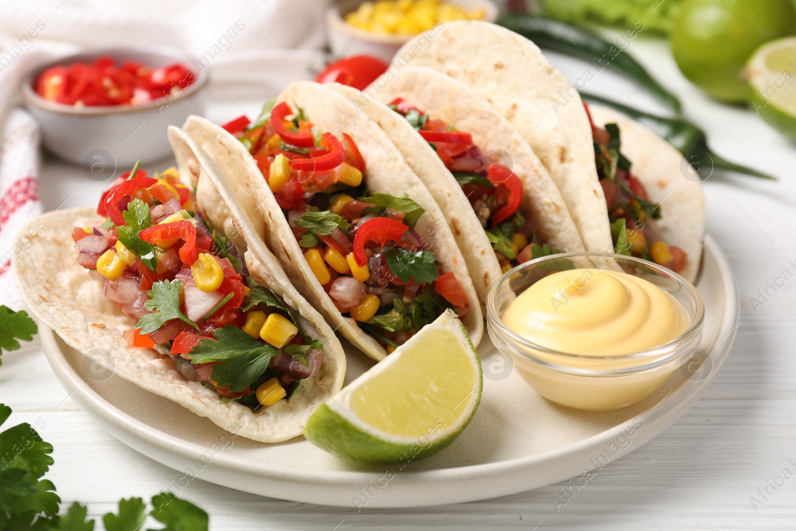 Photo of Tasty tacos with vegetables on white wooden table, closeup