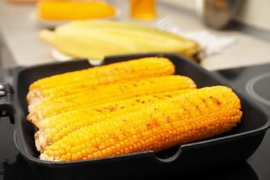 Photo of Cooking fresh corn cobs on grill pan, closeup