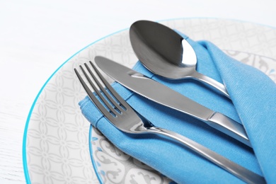 Photo of Plates, cutlery and napkin on white background, closeup. Festive table setting