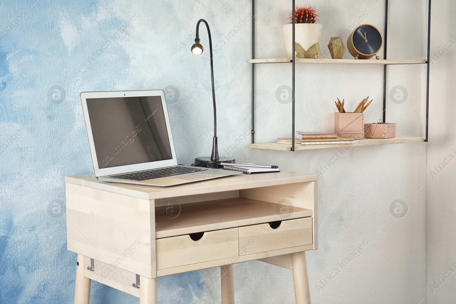 Photo of High wooden table with laptop as stand up workplace in modern interior