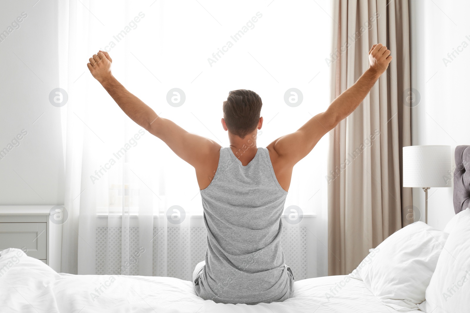 Photo of Man awakening on bed at home. Lazy morning