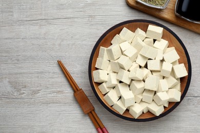 Photo of Delicious tofu and chopsticks on light wooden table, flat lay