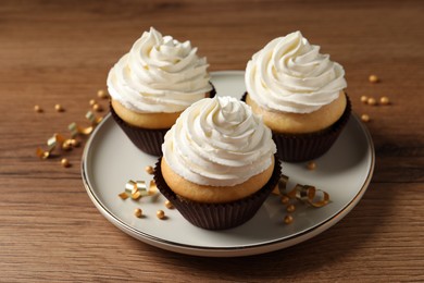 Photo of Delicious cupcakes decorated with cream on wooden table
