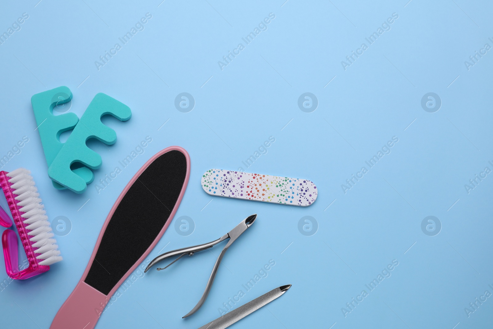 Photo of Set of pedicure tools on light blue background, flat lay. Space for text
