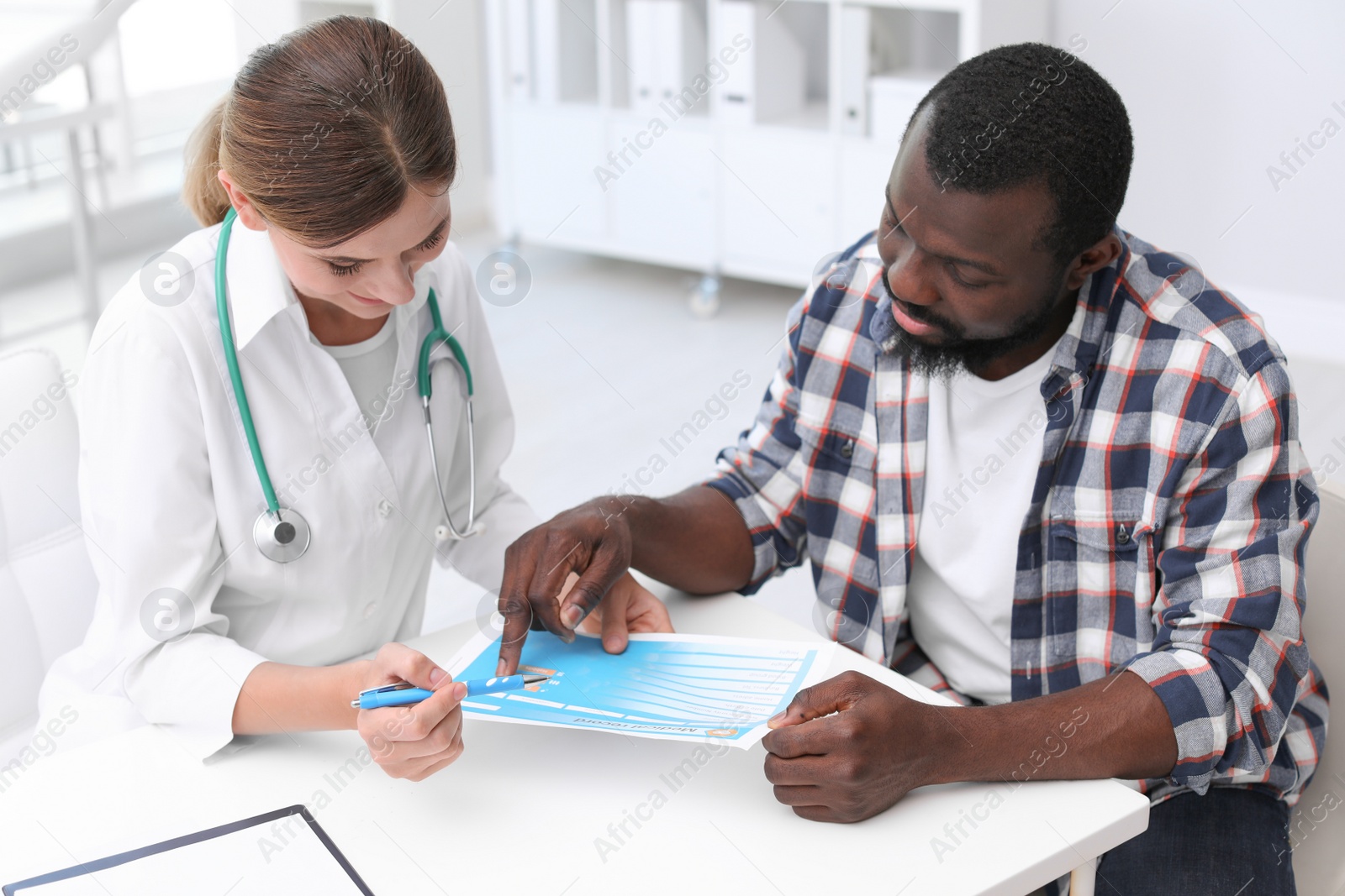 Photo of Young doctor consulting African-American patient in hospital